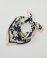 A cream-colored silk scarf with a dark teal floral pattern is tied in a knot against a plain white background. carousel Product Image 1