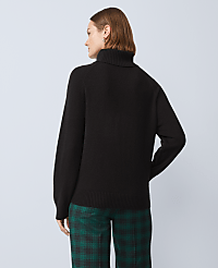 A woman in a black turtleneck sweater and green plaid pants stands against a plain gray background. carousel Product Image 2