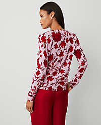 A woman in a pink floral sweater and red pants stands against a plain, light gray background. carousel Product Image 2
