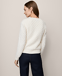 A woman in a textured cream sweater and dark jeans stands against a plain, light-colored background. carousel Product Image 2