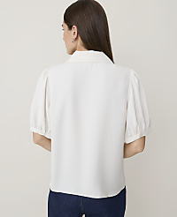 A woman in a white puff-sleeve blouse and dark jeans stands against a plain white background. carousel Product Image 2