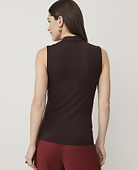 A woman in a brown sleeveless turtleneck and red pants stands against a plain white background. carousel Product Image 2