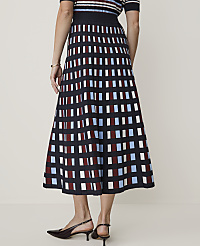 A woman in a checkered skirt and striped top stands against a plain, light-colored background. carousel Product Image 3