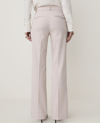 A person stands in front of a plain background wearing high-waisted, wide-leg plaid trousers and a white blouse. carousel Product Image 3
