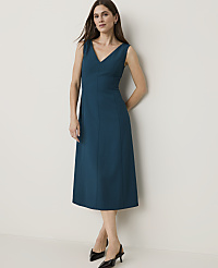 A woman in a teal V-neck dress and black heels stands against a plain, light-colored wall. carousel Product Image 1
