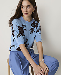 A woman in a light blue floral sweater and matching blue pants sits against a plain, light background. carousel Product Image 3