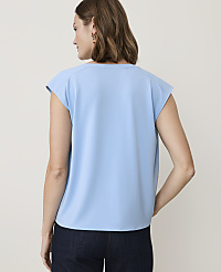 A woman in a light blue top and dark jeans stands against a plain, light background. carousel Product Image 2