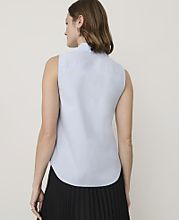 A woman in a light blue sleeveless collared shirt and a black pleated skirt stands against a plain white background. carousel Product Image 2
