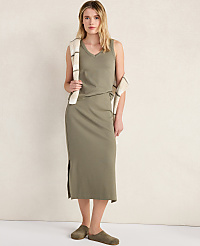 A woman in a green tank dress and clogs stands against a textured, light-colored wall, with a striped scarf draped over her shoulder. carousel Product Image 4