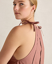 A woman with blonde hair tied in a bun wears a dusty rose halter top with ribbon ties, against a plain, light-colored background. carousel Product Image 4