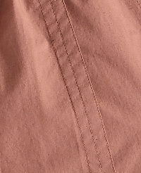 A close-up view of a dusty rose fabric with visible stitching runs diagonally across the frame. carousel Product Image 5