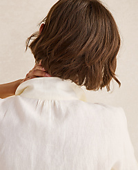 A person's short brown hair is visible in the foreground, touching their neck, against a softly lit, textured beige background. carousel Product Image 3