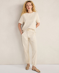 A woman with curly blonde hair stands in a cream-colored outfit against a textured off-white wall. carousel Product Image 2