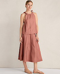 A woman in a rose-colored halter top and skirt stands against a textured, light-colored wall. carousel Product Image 2