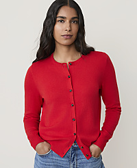 A woman in a red cardigan and blue jeans stands against a plain white background. carousel Product Image 1