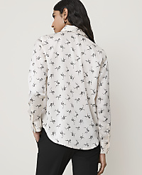 A woman in a white patterned shirt and black pants stands against a plain, light-colored background. carousel Product Image 2