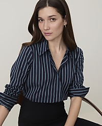 A woman in a striped blouse and black skirt sits in front of a plain background. carousel Product Image 3