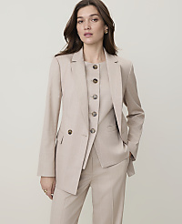 A woman in a beige suit stands against a plain, light-colored background. carousel Product Image 1