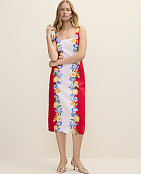 A woman in a floral-print dress stands against a plain, light-colored background. carousel Product Image 1