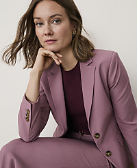 A woman in a mauve blazer and matching pants rests her chin on her hand against a plain, light background. carousel Product Image 3