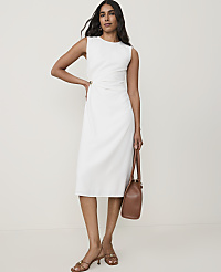 A woman in a white dress and brown sandals stands with a brown purse against a plain background. carousel Product Image 1