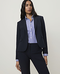 A woman in a navy blazer and striped shirt stands against a plain, light gray background. carousel Product Image 1