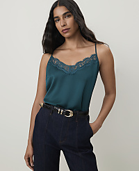 A woman in a teal lace-trimmed camisole and dark jeans stands against a plain gray background. carousel Product Image 1