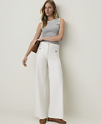 A woman in a striped top and white wide-leg pants stands against a plain white background, holding a brown clutch. carousel Product Image 1