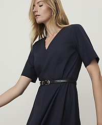 A woman in a navy dress with a black belt is shown against a plain, light background. carousel Product Image 3