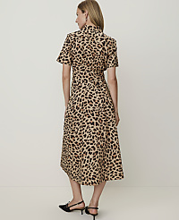 A woman in a leopard print dress stands against a plain, light-colored background. carousel Product Image 2