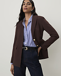 A woman in a brown blazer and striped shirt stands against a plain gray background. carousel Product Image 1