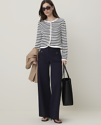 A woman in a striped cardigan and wide-leg pants stands against a plain, light-colored background, holding a tote bag and a jacket. carousel Product Image 3