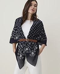 A woman in a white top and white pants wears a dark blue patterned scarf cinched with a brown belt, against a plain white background. carousel Product Image 1