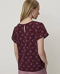 A woman in a burgundy floral top stands against a plain, light-colored background. carousel Product Image 2
