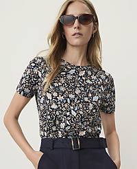 A woman in a floral t-shirt and sunglasses poses against a plain, light-colored background. carousel Product Image 1