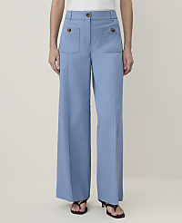 A person stands in light blue wide-leg pants with patch pockets and dark sandals against a plain, light background. carousel Product Image 2