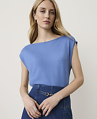 A woman in a blue top and denim skirt stands against a plain background. carousel Product Image 1