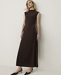A woman in a brown dress stands against a plain white wall. carousel Product Image 1