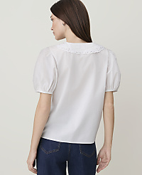 A woman in a white puff-sleeved blouse with a lace collar and dark jeans stands against a plain white background. carousel Product Image 2