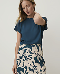 A woman in a teal top and a floral skirt stands against a plain background. carousel Product Image 1