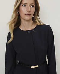 A blonde woman in a navy jacket with a gold-buckled belt stands against a plain white background. carousel Product Image 3