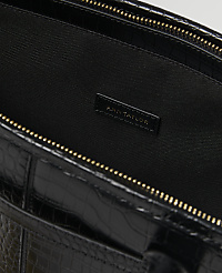 A black crocodile-embossed leather bag with a gold zipper is shown against a dark, textured background with the "Ann Taylor" logo visible inside. carousel Product Image 2