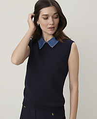 A woman in a navy sweater vest over a denim collar stands against a plain white background. carousel Product Image 1