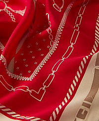 A vibrant red silk scarf with a chain and buckle pattern in the foreground is set against a creamy background with a similar design. carousel Product Image 2