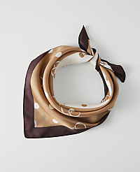A silk scarf with a polka dot and chain pattern is tied in a knot against a plain white background. carousel Product Image 1