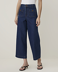 A person models wide-leg denim culottes with patch pockets and black heeled sandals against a plain, light-colored background. carousel Product Image 2