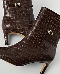 A pair of glossy brown crocodile-embossed ankle boots with gold buckles are displayed against a plain white background. carousel Product Image 2