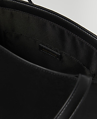 A black Ann Taylor tote bag is shown with its interior lining and a small pocket visible in the foreground, against a dark, out-of-focus background. carousel Product Image 2