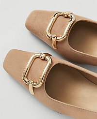 Two tan suede flats with gold buckle details are in the foreground against a plain white background. carousel Product Image 2