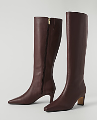A pair of burgundy leather knee-high boots with pointed toes and block heels stand on a plain white background. carousel Product Image 2